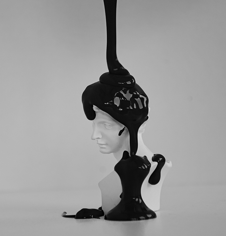 Escultura blanca de un rostro, cubierta de pintura negra que gotea.